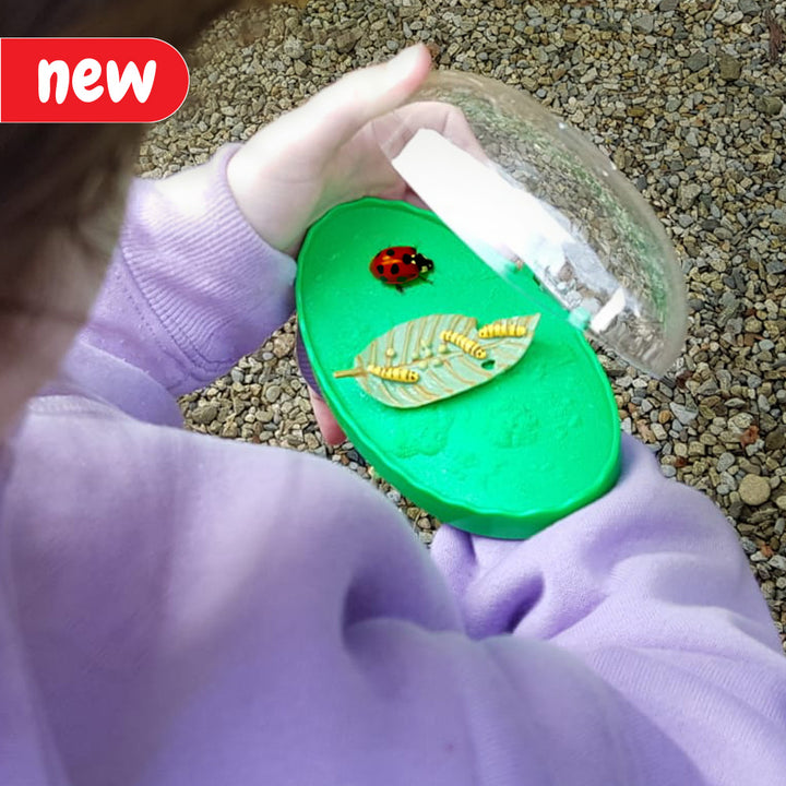 A child wearing the Catch a Bug Wrist Viewer, examining an insect up close. The viewer is equipped with a convenient wrist strap for easy use. Ideal for curious minds and nature enthusiasts interested in observing tiny insect details without causing harm