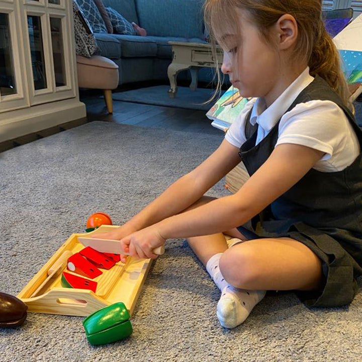 Wooden fruit and vegetable tray with VELCRO® pads, allowing children to safely cut through and reassemble the pieces using the included wooden knife. Promotes coordination skills, understanding of proportion, division, and illustrates simple fractions thr